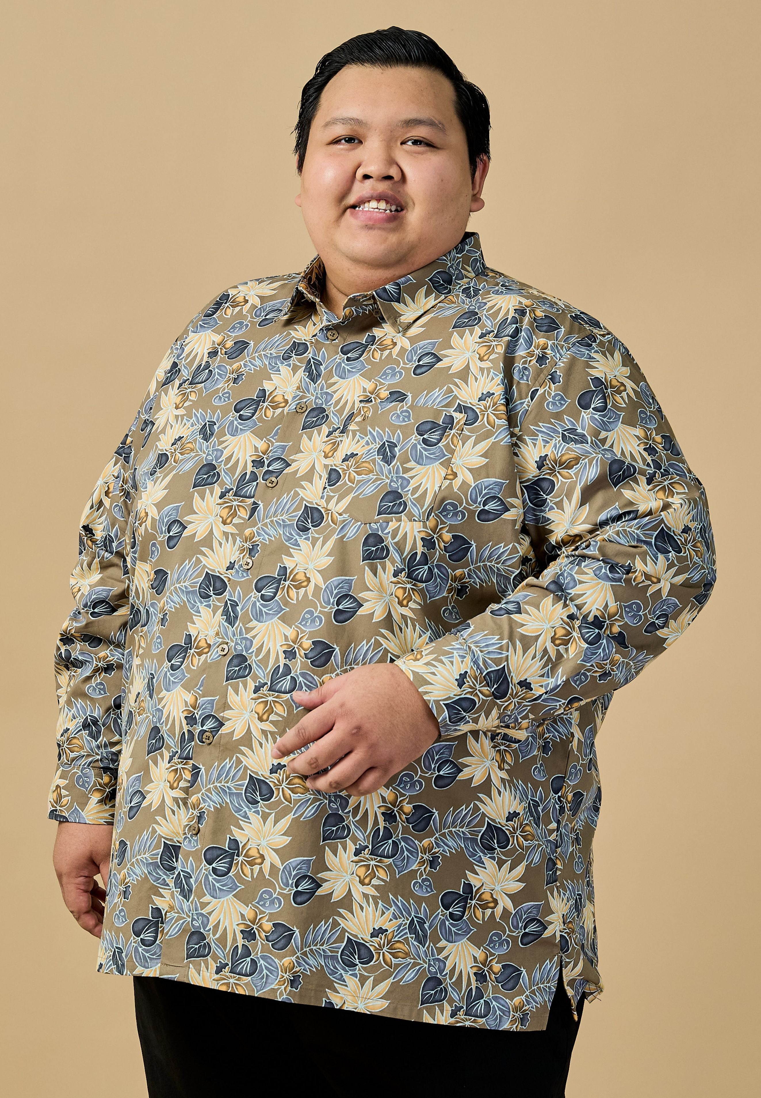 A plus-size male model wearing a blue floral long sleeves shirt and black pants poses highlighting a fashionable and vibrant look #color_olive green